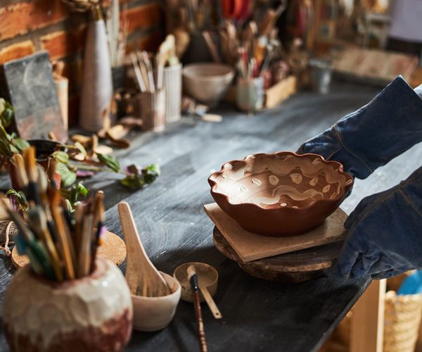 potter-hands-placing-painted-bowl-on-table-in-pott-resize.jpg